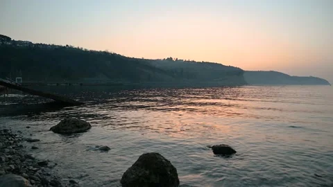 Calm waves gently hitting coastline at sunset Stock Footage 150887729