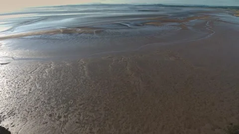 Calm waves gently lap against the sandy shore at sunset Stock Footage 320266218