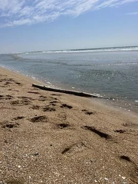 Calm Waves Lap Against the Sandy Shore on a Sunny Beach Day Foto stock