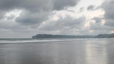 Calm waves, light, and cliffs with a cloudy sky in the background Stock Footage 340005056