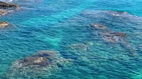 Calm waves over the rocks in turquoise  color sea or ocean Stock Footage 198574207