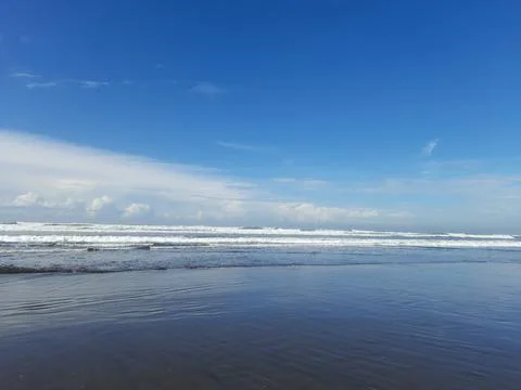 Calm waves rolling onto a wide sandy beach Stock Photos