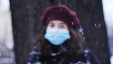 Calm winter scene with snow falling in front of woman with face mask. Stock Footage 147159015