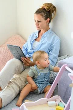 Calm woman using tablet while spending time with child Stock Photos
