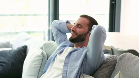 Calm young bearded man resting on couch Vídeos de archivo 335588129