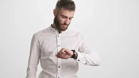 A calm young bearded man is using his smart watch isolated over white background Stock Footage 125320713