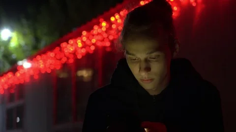 Calm young boy using smartphone at night, fair red lights bg, 4k footage Stock Footage 98878724