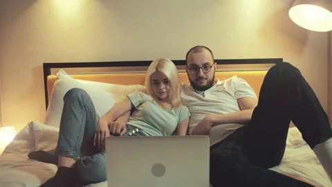 Calm young couple lying on couch at home looking at laptop Stock Footage 230379492