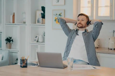 Calm young freelancer resting while sitting at his workplace at home Stock Photos