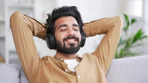Calm young handsome bearded man in wireless headphones listening to relaxing  Stock Footage 252202501
