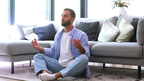 Calm young man practicing yoga meditation in the lotus position with eyes Stock Footage 344781475