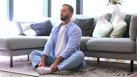 Calm young man sitting on the floor in lotus position with his eyes closed Stock Footage 344781608