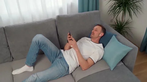 Calm young man wearing wireless headphones relaxing while listening to music Stock Footage 152964897