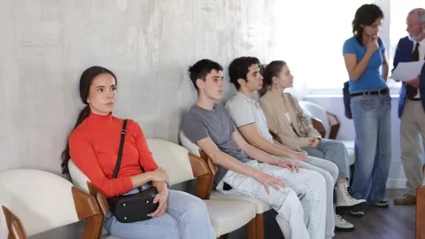 Calm young people sitting in a queue while manager talking with visitor in Video stock 345583686
