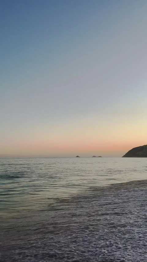 Calming ocean waves crashing on a sandy rio de janeiro beach at sunset Video stock 323407785