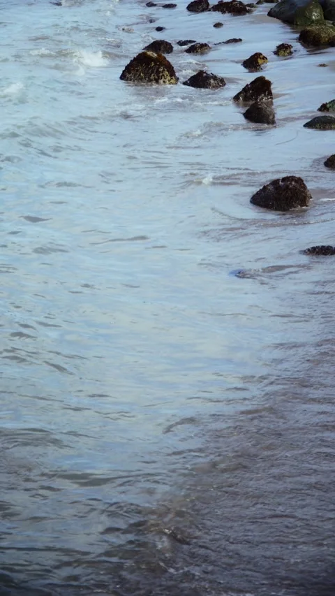Calming ocean waves washing over a rocky shoreline Video stock 326228068