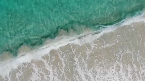 Calming turquoise ocean waves mixed with sand from a drone Stock Footage 170084096