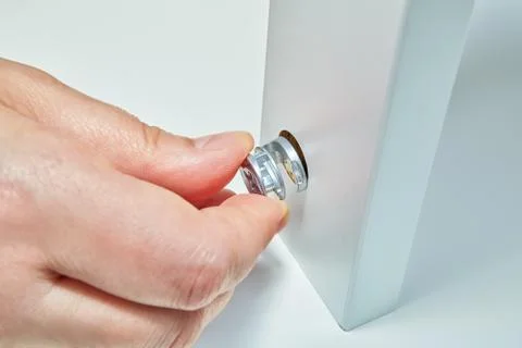 Cam lock nut in hand of flat pack furniture assembler. Stock Photos