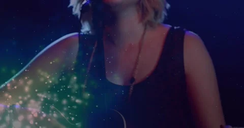 Cam pulling back revealing female with blue sparkles strumming guitar and Video stock 333900278