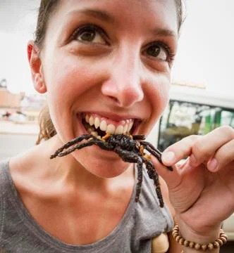 Cambodia, young woman eating fried tarantula spiders Stock Photos