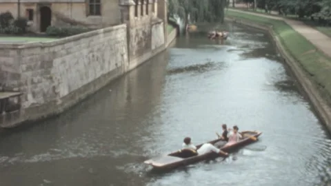 Cambridge - 1965: Students punt on a river with university buildings background Stock Footage 282088874