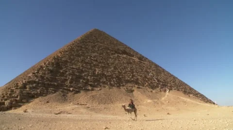 Camel rider at iconic Great Pyramid of Giza, Egypt desert - wonders of the world Stock Footage