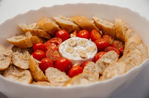 Camembert cheese baked with tomatoes and baguette, herbs and garlic. An Stock Photos