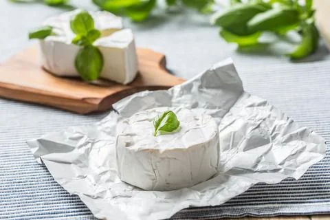 Camembert or brie cheese with basil leaves on table Stock Photos