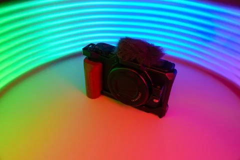 A camera against a background of multicolored neon rays Stock Photos