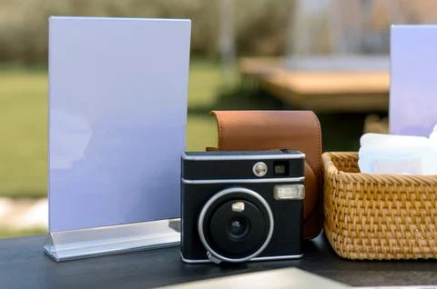 Camera and blank sign on table with wicker basket in outdoor setting Stock Photos