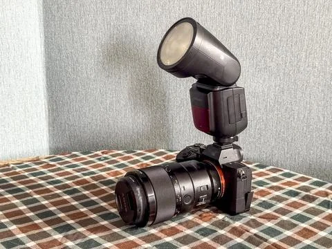 Camera and flash set up on a table in indoor setting Stock Photos