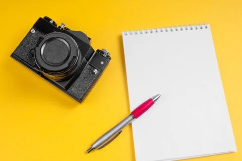 Camera and notebook with pen on a yellow background. Mock-up. Photo concept. Stock Photos