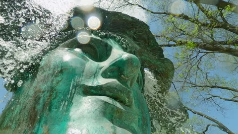 Camera approaches close from below to the bronze mask fountain, splashes of Stock Footage 295267376