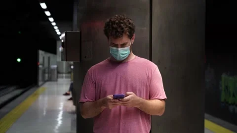 Camera approaches to a man using his smartphone while standing on a train sta 스톡 동영상 133499177