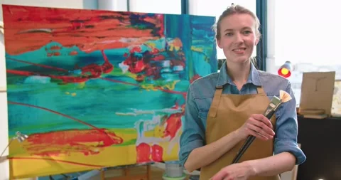 Camera approaching Caucasian joyful young pretty woman talented painter in apron Stock Footage 149572236