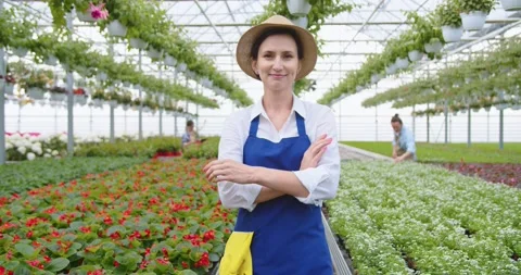 Camera approaching happy young beautiful Caucasian female garden center owner in Stock Footage 157386882