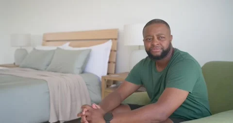 Camera approaching, man sitting up in green armchair in bedroom, smiling, Stock Footage 340011400
