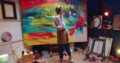 Camera approaching young joyful pretty Caucasian female painter drawing creating Stock Footage 149579186