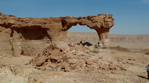 The camera ascends over escarpment and flies through The Natural Arch of Riyadh Stock Footage 153038653