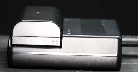 Camera battery being placed in the charger close-up isolated on black Stock Footage 207930631