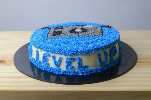 Camera birthday cake from a high angle. "Level up" word in blue letters. Home Stock Photos
