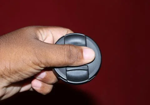 Camera cap to hold on the hand with red background. Stock Photos