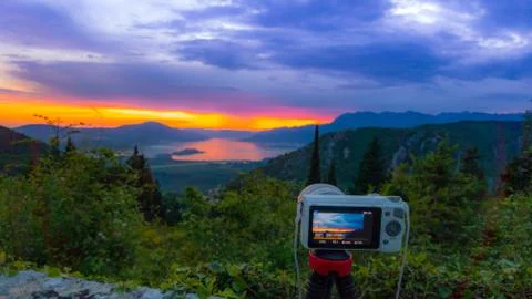 Camera capturing sunset shot. Photography using on tripod against sun rays wi 스톡 사진