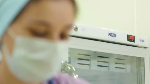 Camera Changes Focus from Pozis Fridge to Nurse in Mask Stock Footage 77032736
