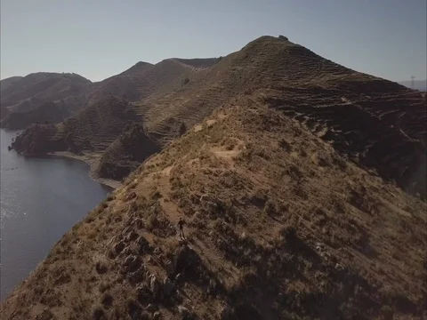 Camera circles around hikers overlooking lake Titicaca from Isla del Sol Stock Footage 83286896