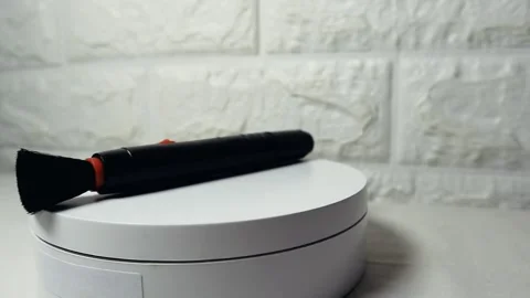 Camera cleaning tool rotating on a white surface, showcasing its sleek desi.. Stock Footage 297152162