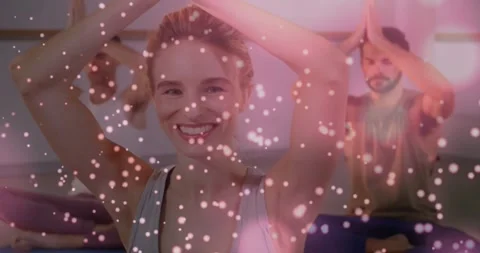 Camera closing in woman and class joining palms overhead in yoga pink petals Stock Footage 332286071