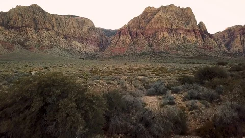 Camera cranes up from desert floor to reveal a hiking trail leading to mountains Video stock 105019983