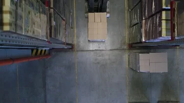 Camera cranes up on shelves of cardboard boxes inside a storage warehouse. Stockbeeldmateriaal 85746286