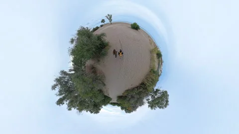 The camera creates a Tiny Planet effect, wrapping the sandy path, trees, and two Stock Footage 293106374